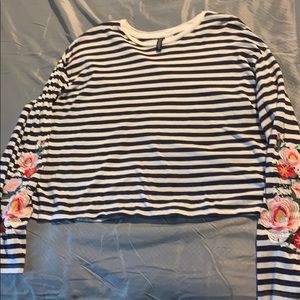 Cropped long sleeved shirt with floral embroidery.